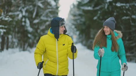 Ein-Mann-In-Einer-Gelben-Jacke-Und-Eine-Frau-In-Einem-Blauen-Overall-Im-Winter-Im-Wald-Beim-Skifahren-In-Zeitlupe